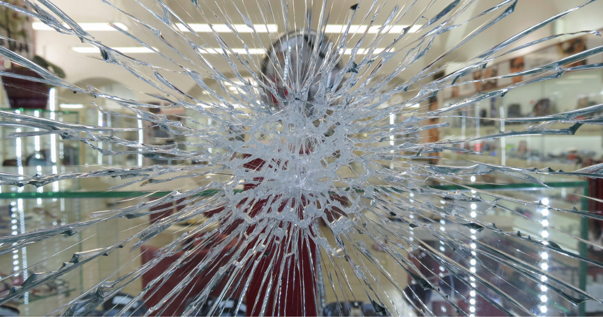 Spider-web cracked glass holding together after impact at a commercial storefront